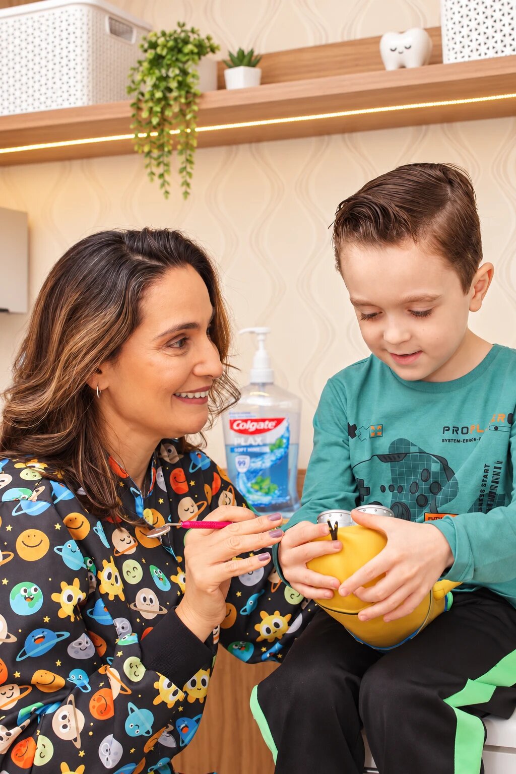 Dra. Viviane mostra o espelho clínico a um menino que segura um brinquedo