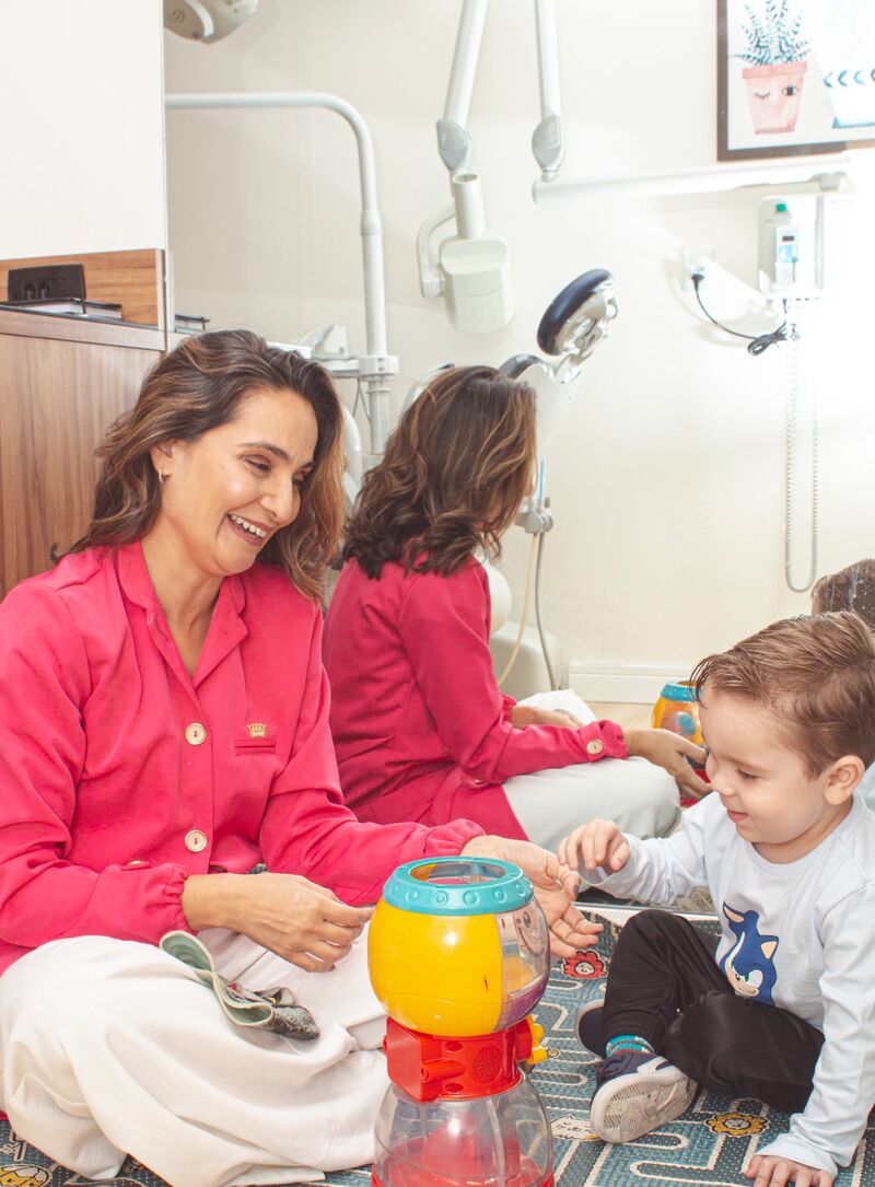 Dra. Viviane brinca com um menino no tapete do consultório
